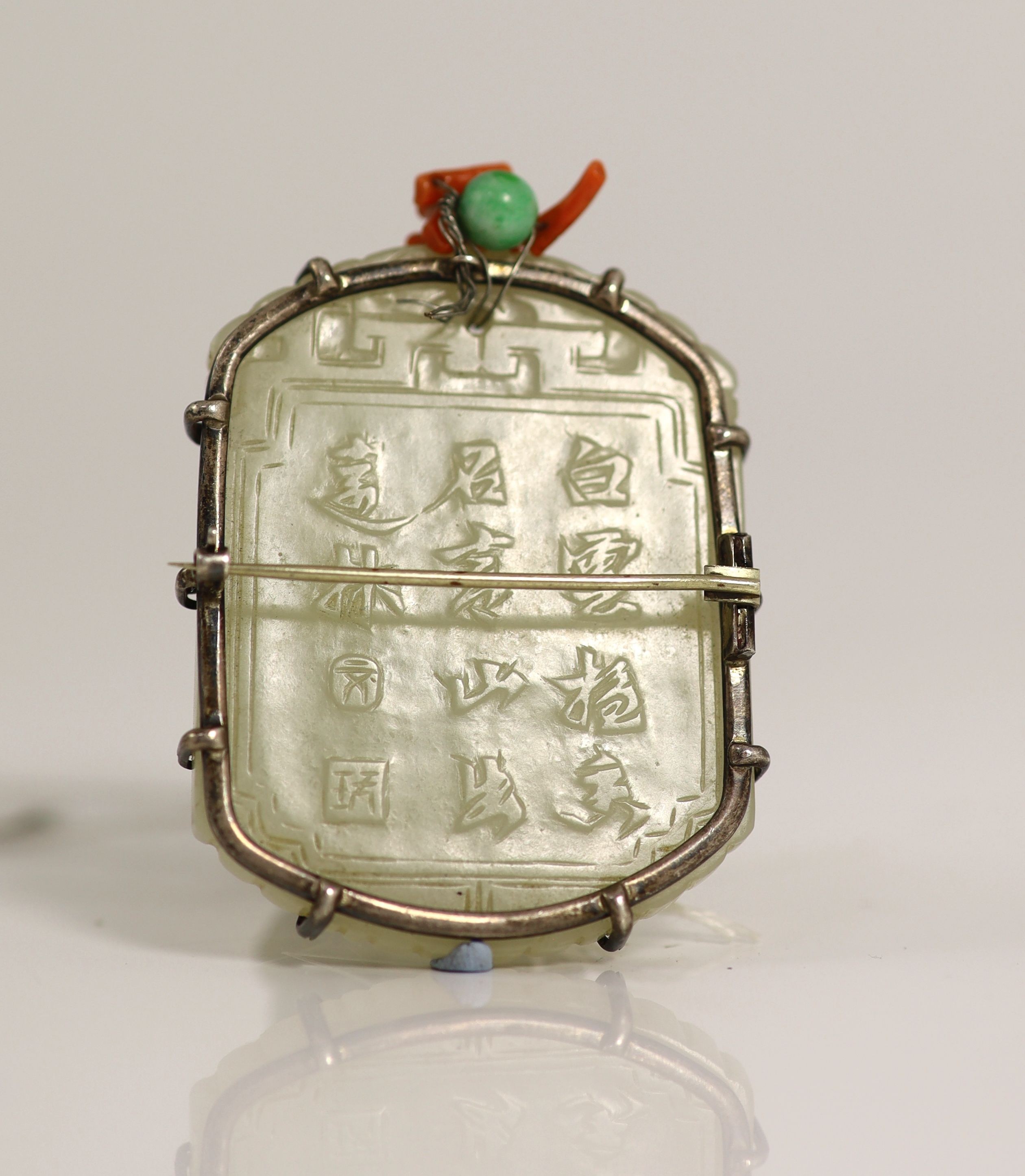 A Chinese pale celadon jade plaque, 19th century, 5.5 cm high, later white metal brooch mount